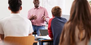 teacher-standing-at-front-of-college-students-for-PLMC7VR